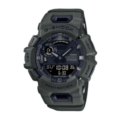 A CASIO G-SHOCK watch with a dark green resin band and case, featuring a digital display and analog hands.