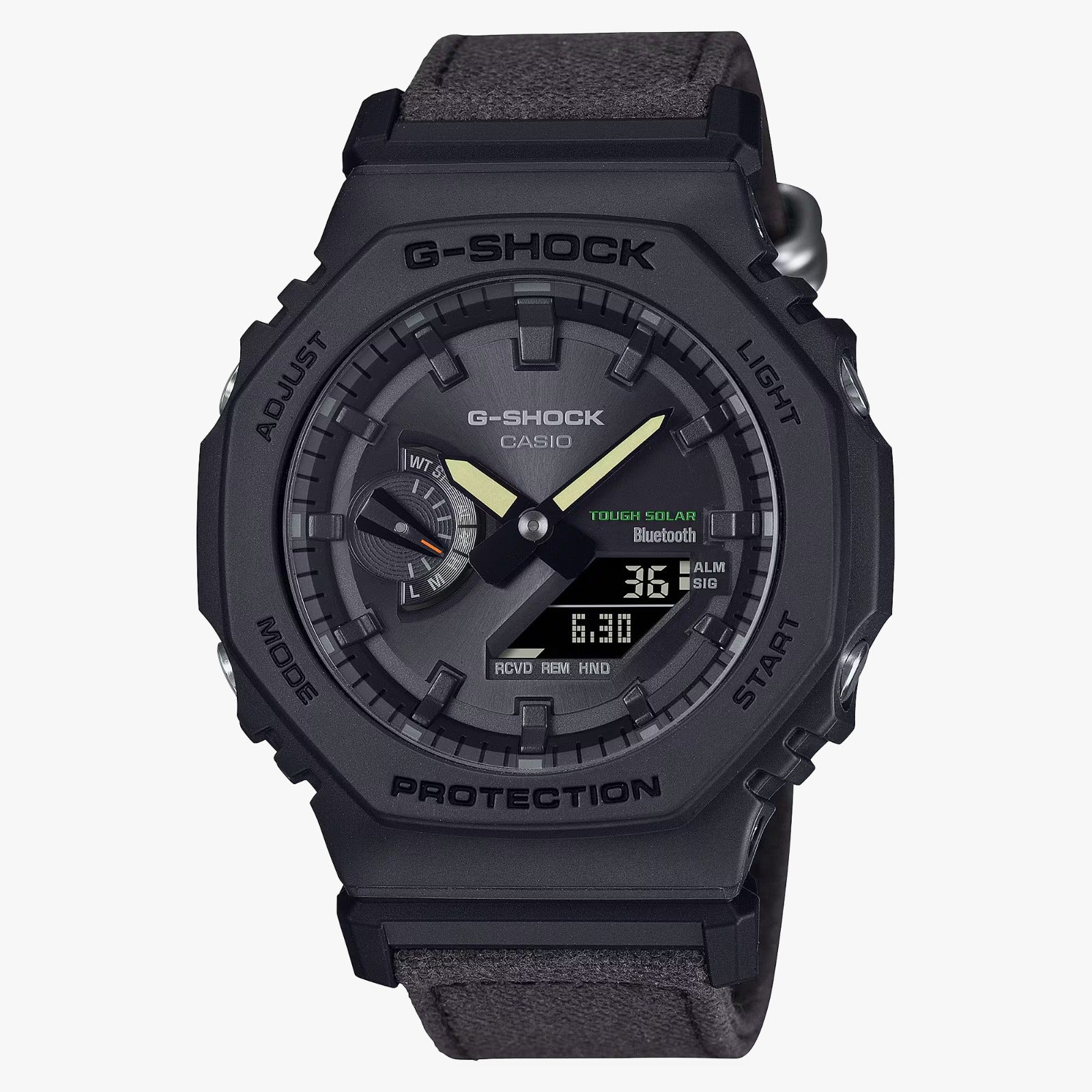 A black CASIO G-SHOCK watch with a digital display and analog hands, featuring a carbon case and a black cloth band.