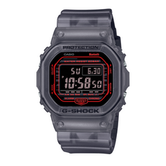 A digital CASIO G-SHOCK watch with a black resin band and case, featuring a digital display showing time and various watch features, housed in a transparent case.