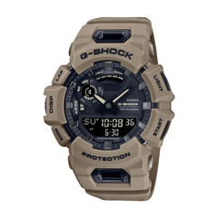 A Casio G-Shock watch with a beige resin band and case, digital display showing time and various watch features, and mineral glass.