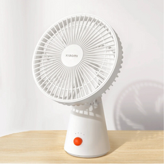 A white Xiaomi rechargeable mini fan placed on a wooden surface, with a simple and compact design.
