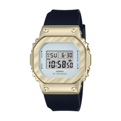A digital CASIO G-SHOCK watch with a gold ion plated bezel and a black resin band, displaying a digital screen.