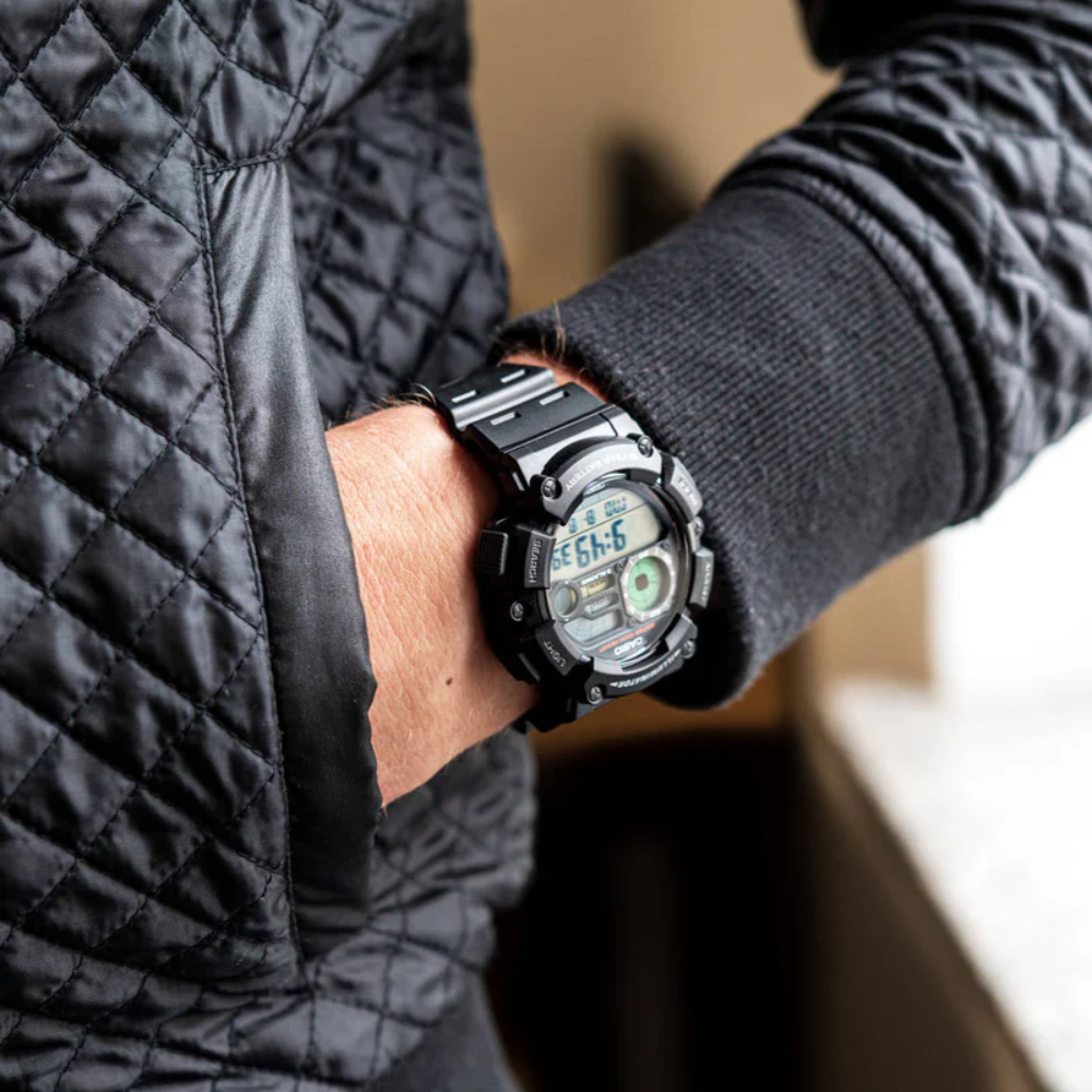 Person wearing a black digital watch with a quilted jacket