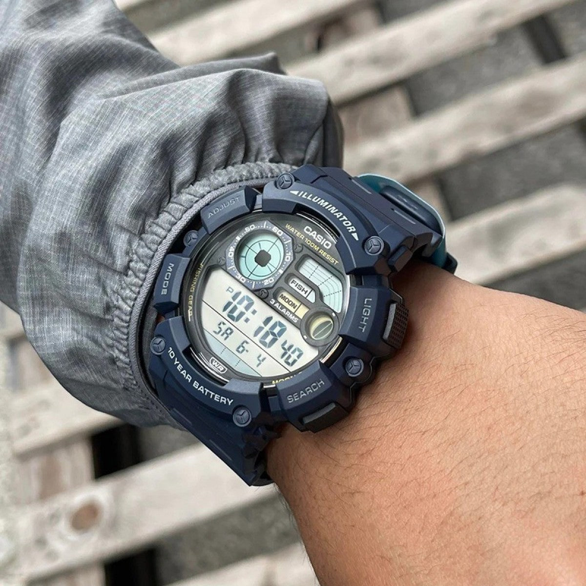 Person wearing a Casio digital watch on wrist with blurred background